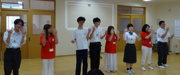 参加者全員で歌を歌っている。曲は、明日はきっといい日になる