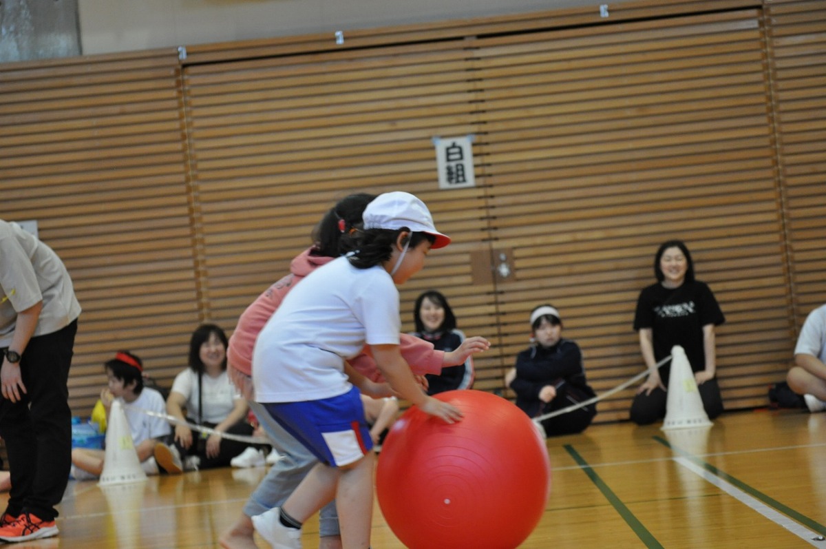 赤いボールを小学部2年生と借り人のお客さんが一緒に転がしています。