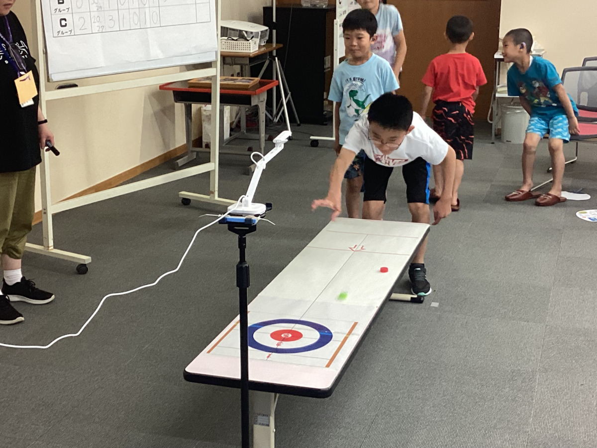 交流会のレクリエーション「ペットボトルキャップカーリング」で遊んでいる様子