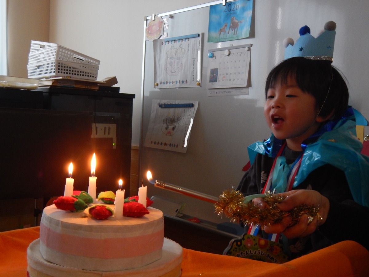 誕生ケーキのろうそくに火を着けている場面の写真