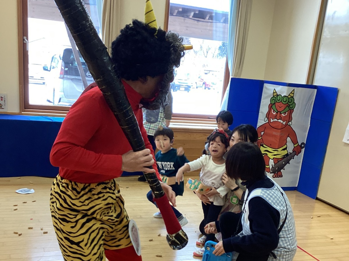 赤鬼に幼児３人が豆をまいている写真