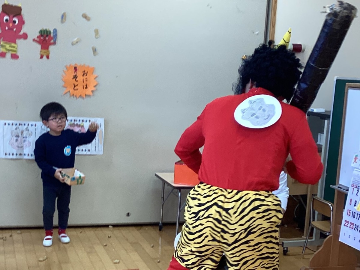 赤鬼に豆をまいている年少児の写真