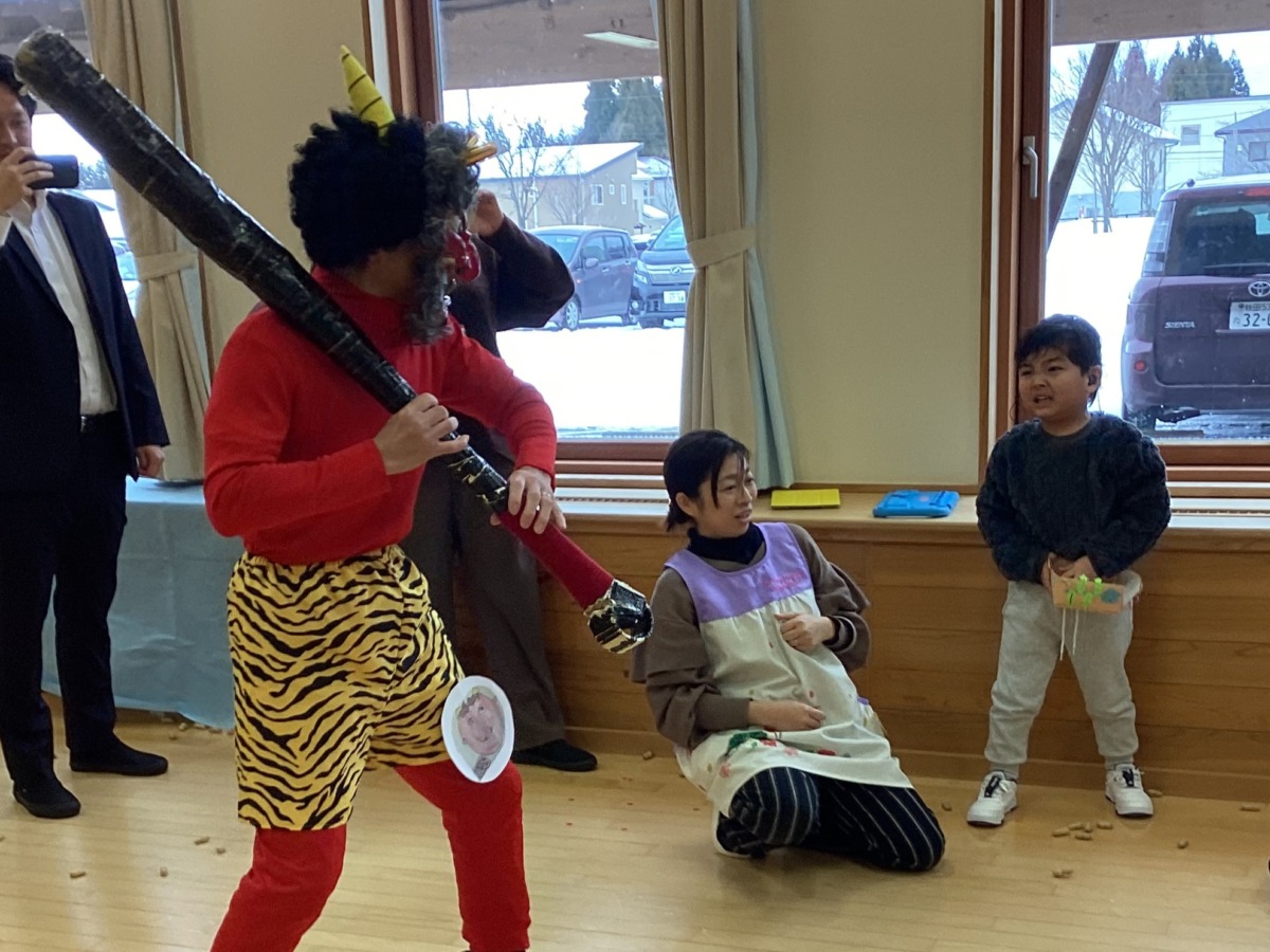 赤鬼に豆をまいている年中児の写真