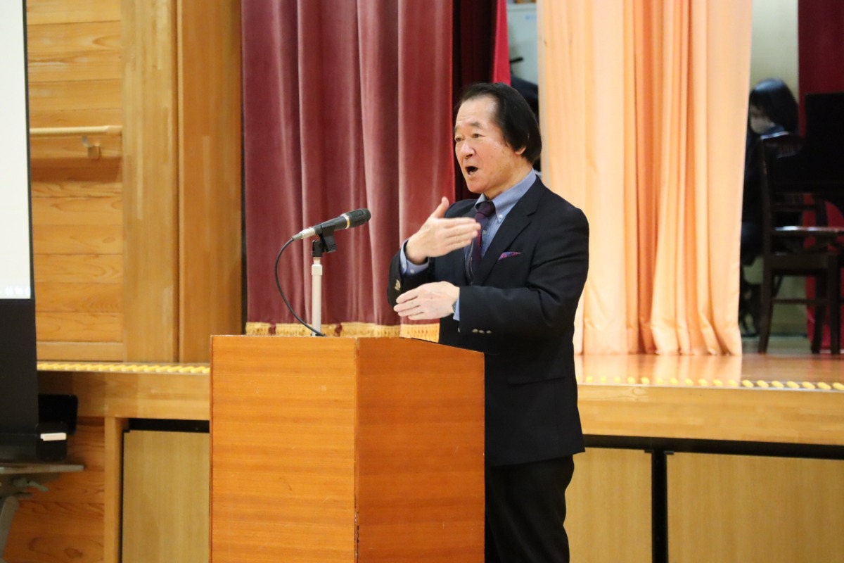 お祝いの言葉を話す同窓会長の写真