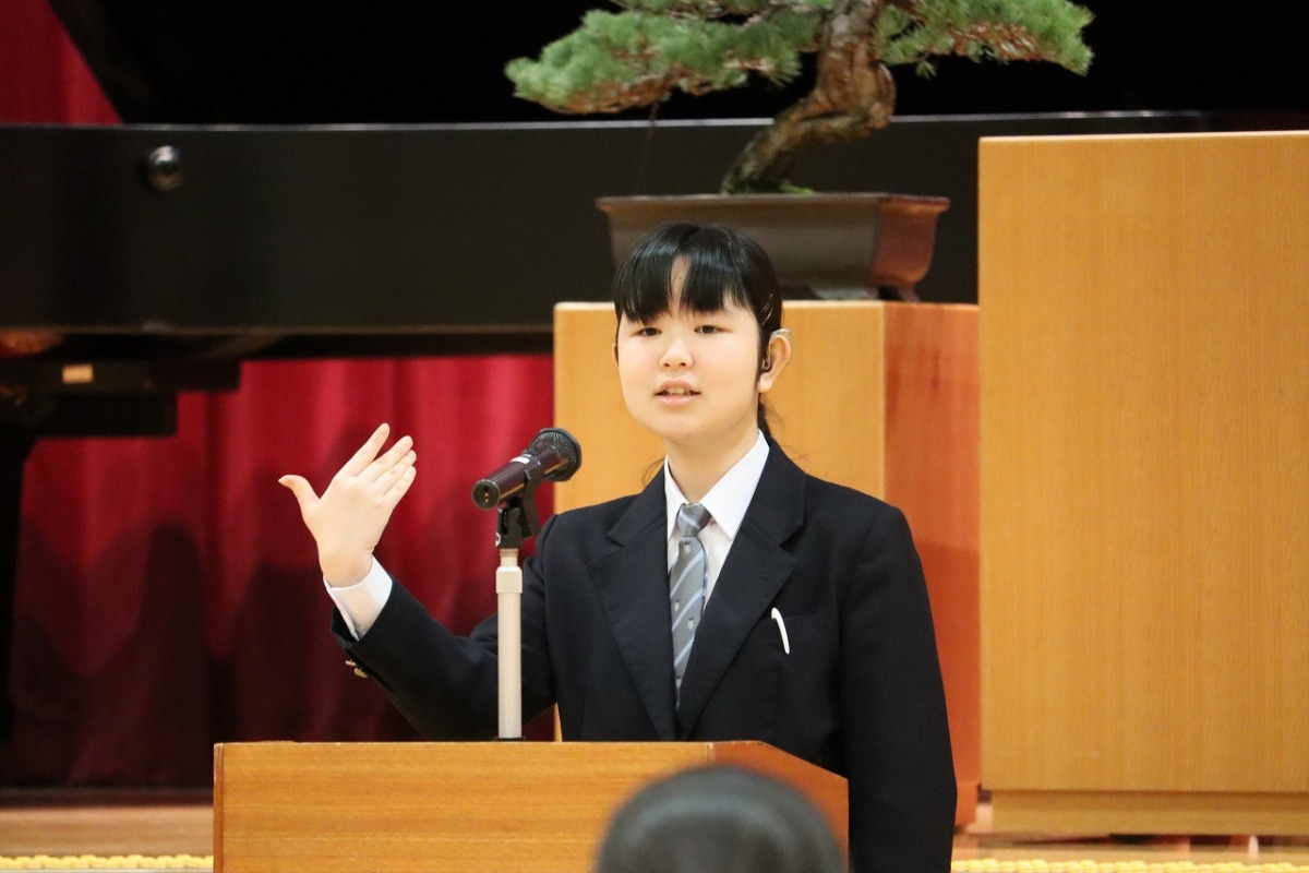 高等部生徒会長が在校生代表歓迎のことばを演台の前で述べている写真