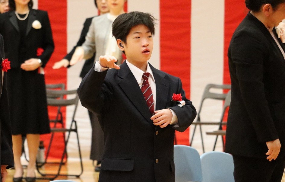 中学部の新入生１名が校歌を手話を用いて歌っている写真