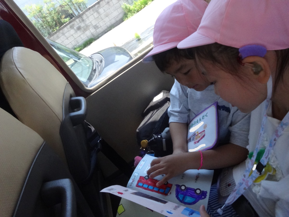 バスの中で幼児同士でしおりを見ている写真