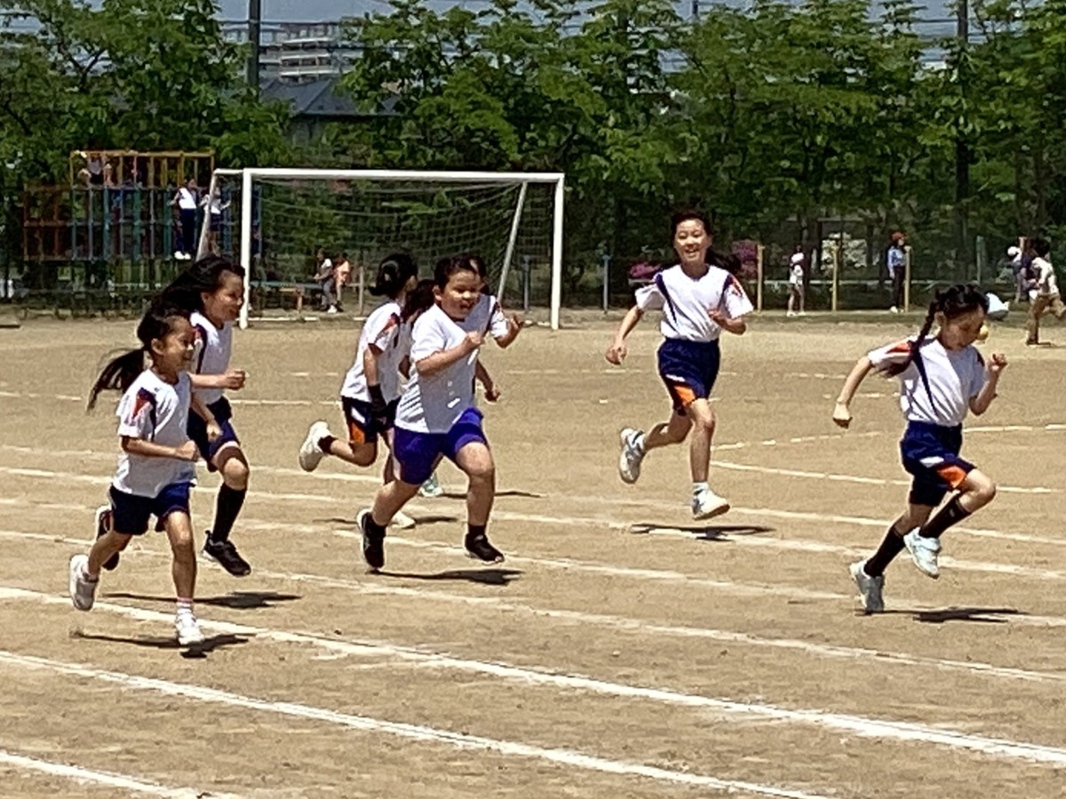 休み時間、友達に誘われて一緒にかけっこをしている写真