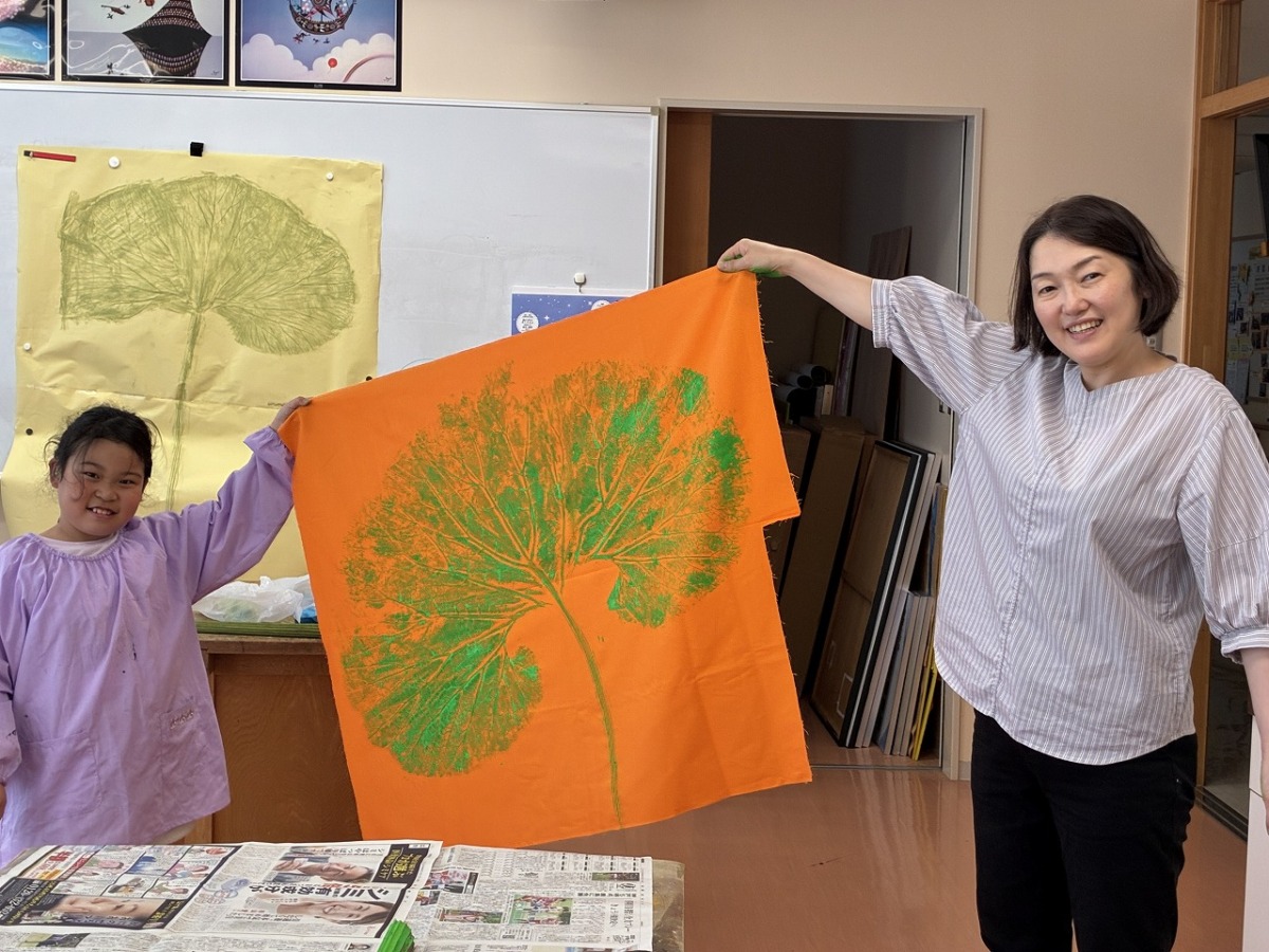 ふき刷りをして、児童と先生が一緒に作品を笑顔でもっている様子です。