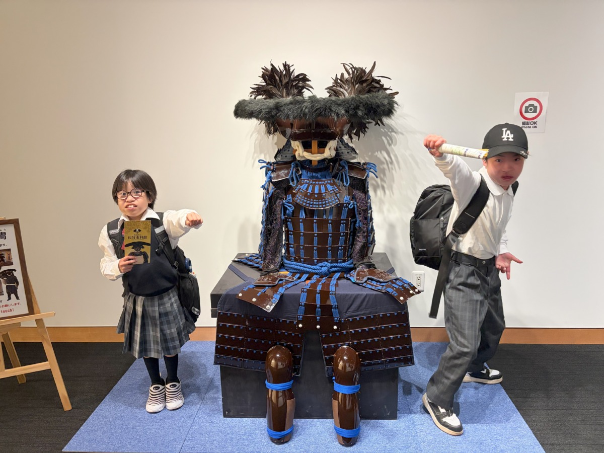 佐竹資料館の甲冑を挟んで中学部1年生の２名がポーズをとっている写真