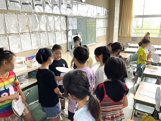 女の子が友達からうちわをもらっている写真