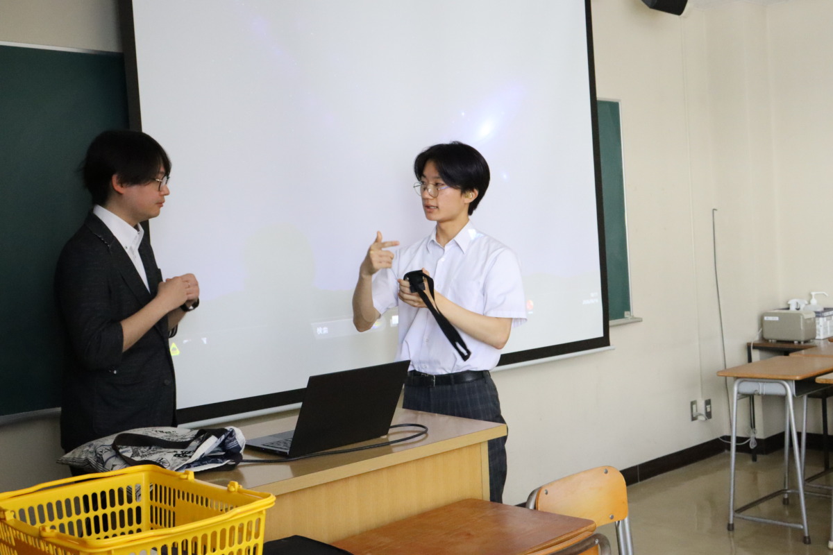模擬講義が始まる前に、模擬講義を担当してくださる先生に対して、生徒が音声補聴システムのロジャーマイクを手渡しています。