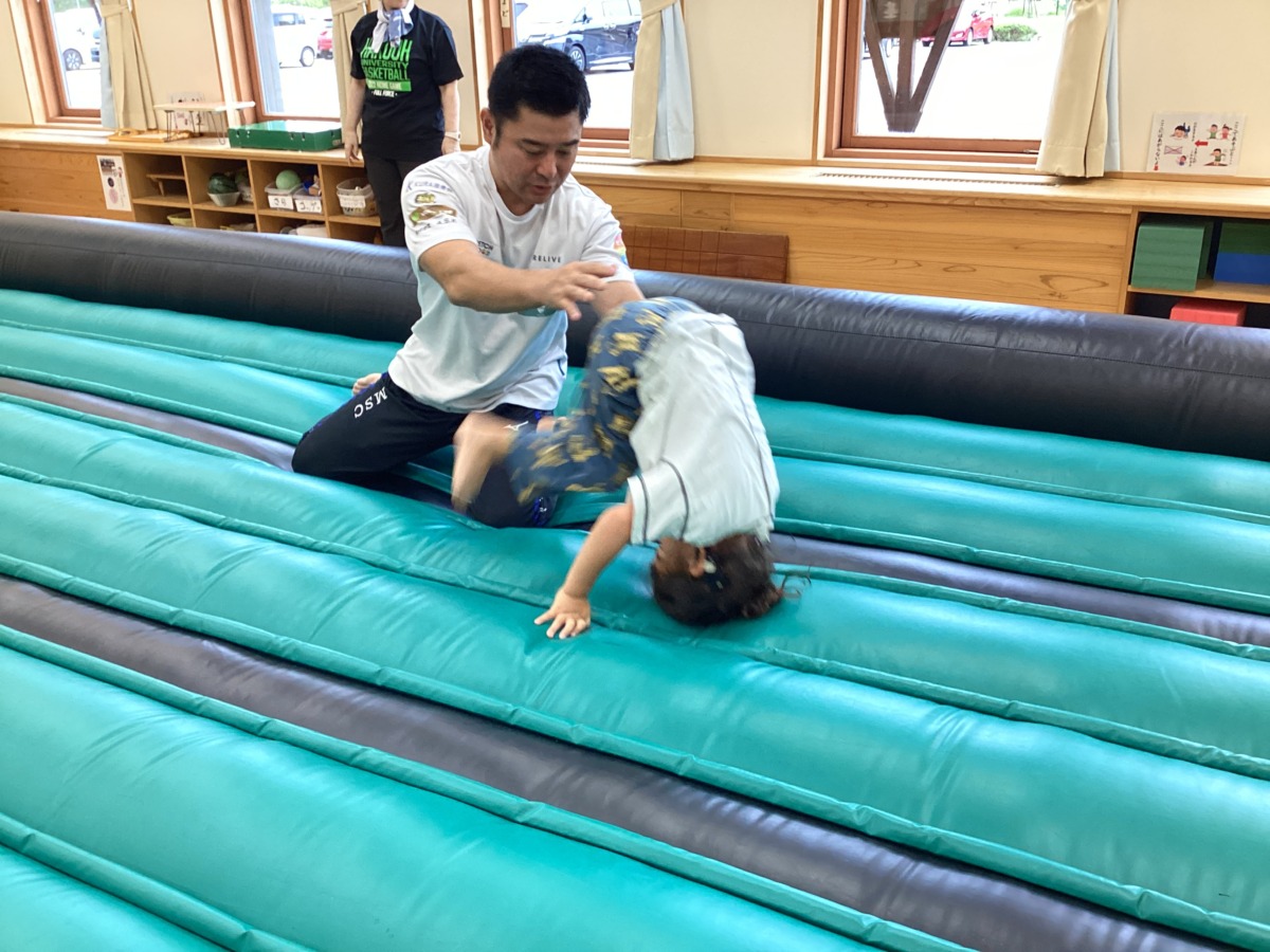 エアートランポリンの上で松村先生に補助してもらいながら男の子が前転している写真