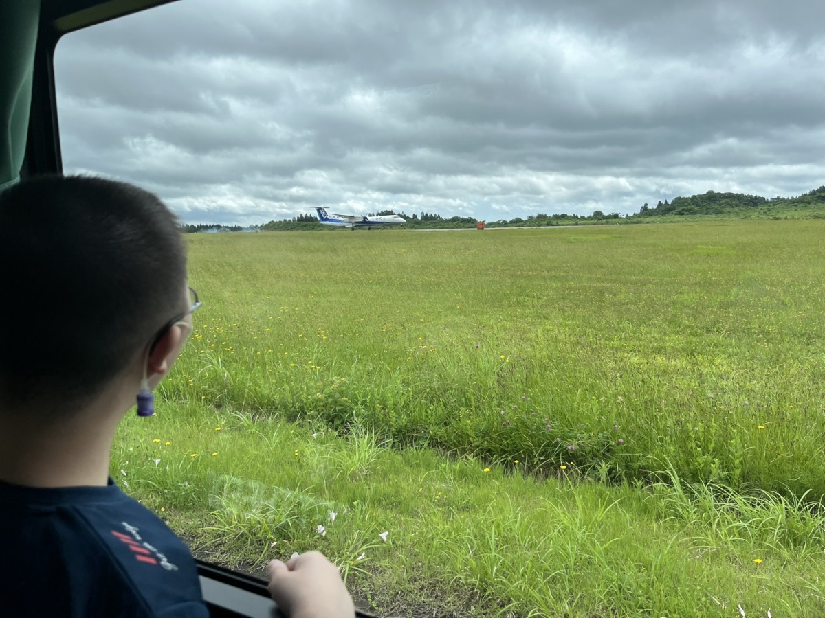 【写真】滑走路の横で飛行機を見る児童