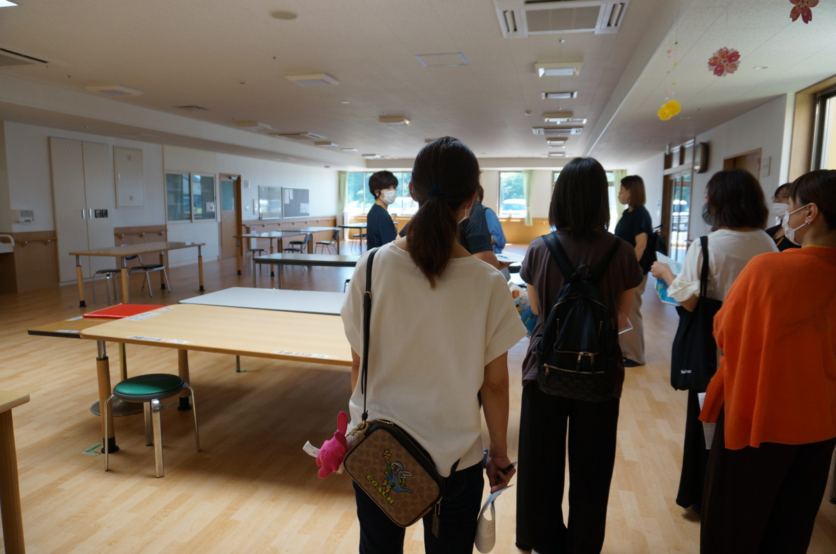 写真:食堂で、施設の方から説明を聞く保護者。