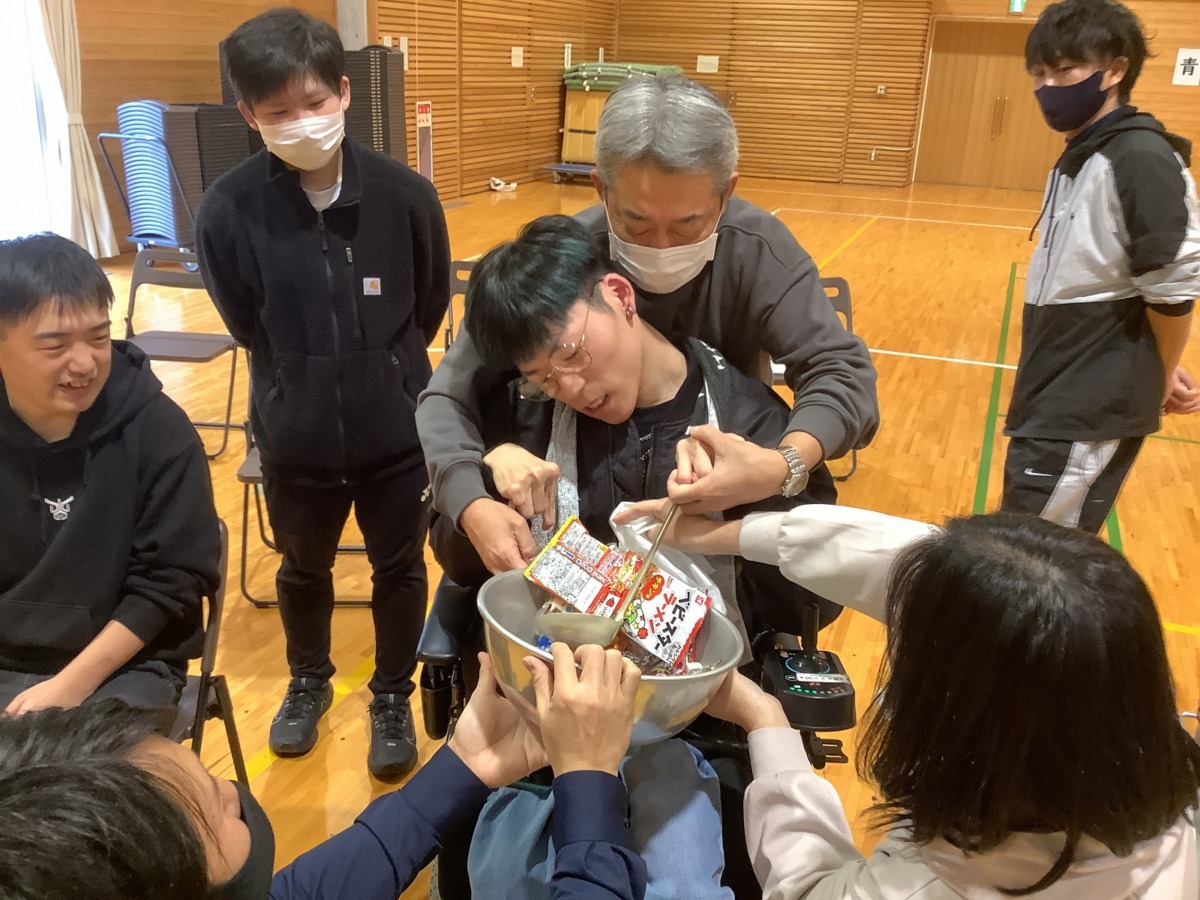 写真:お玉でお菓子をすくおうとする同窓生