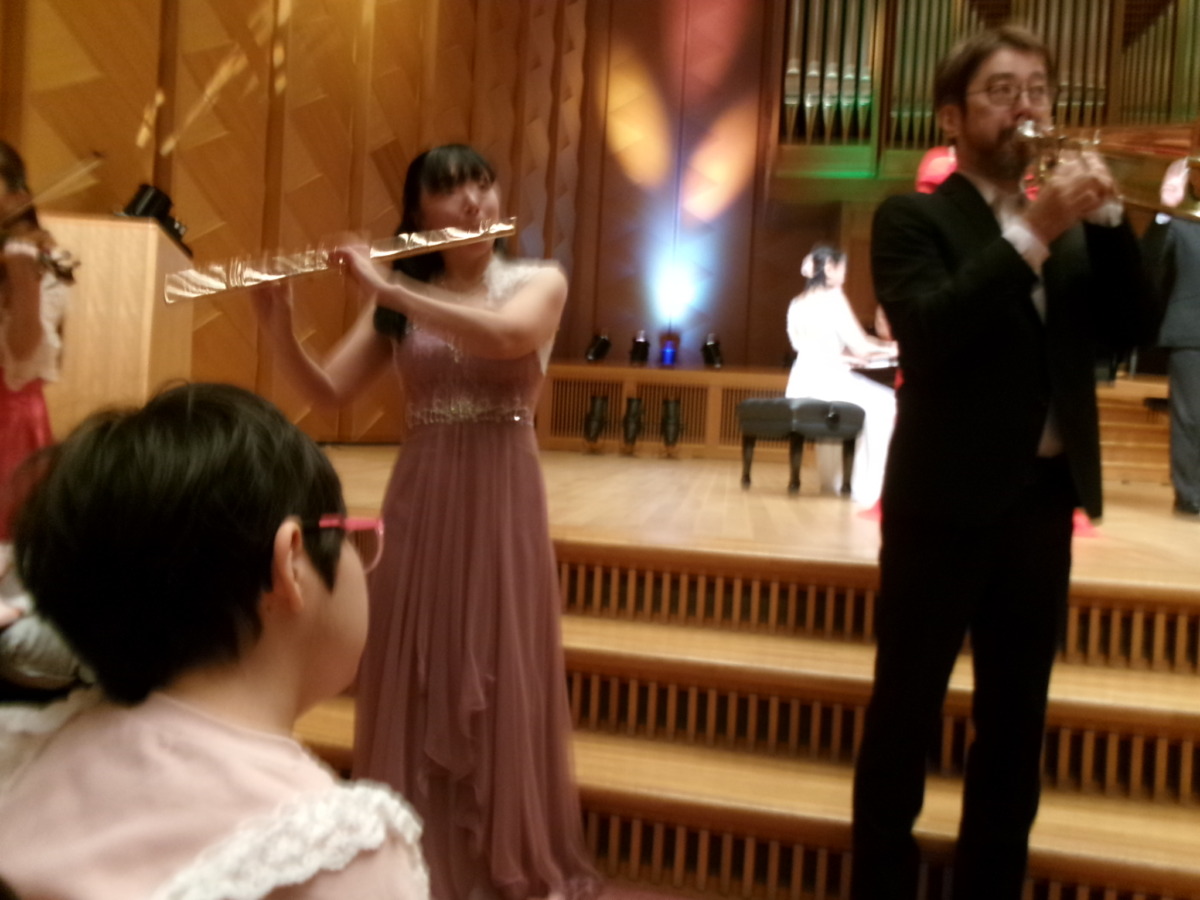 写真:フルートとトランペットの演奏を聴く児童