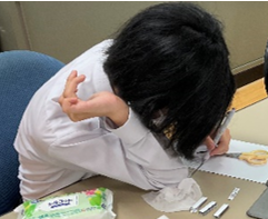 写真：右肘で台紙を押さえながら作業をする生徒