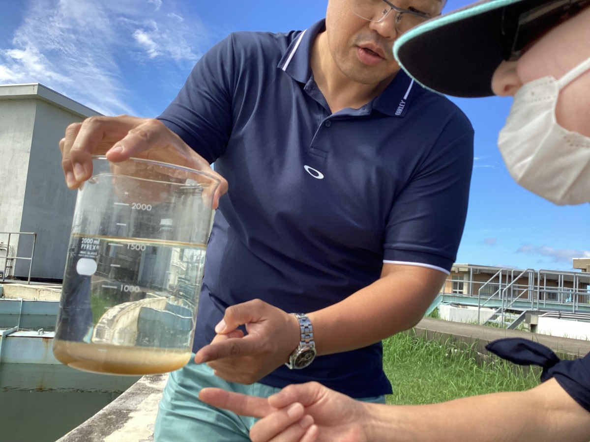 写真:ビーカーで水の汚れ(沈殿物)を確認する様子