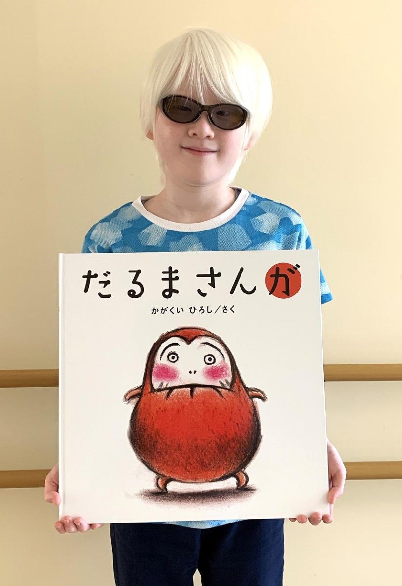 こんなに大きな絵本です（肩幅ほどの大きさの絵本をもつ小学生）