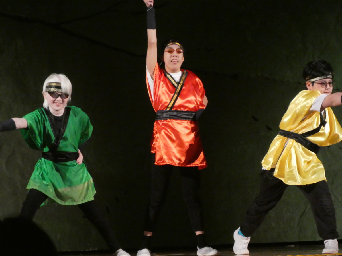 赤・緑・黄色の着物を身にまとった忍者役の児童が、ダンス後にポーズをしている様子