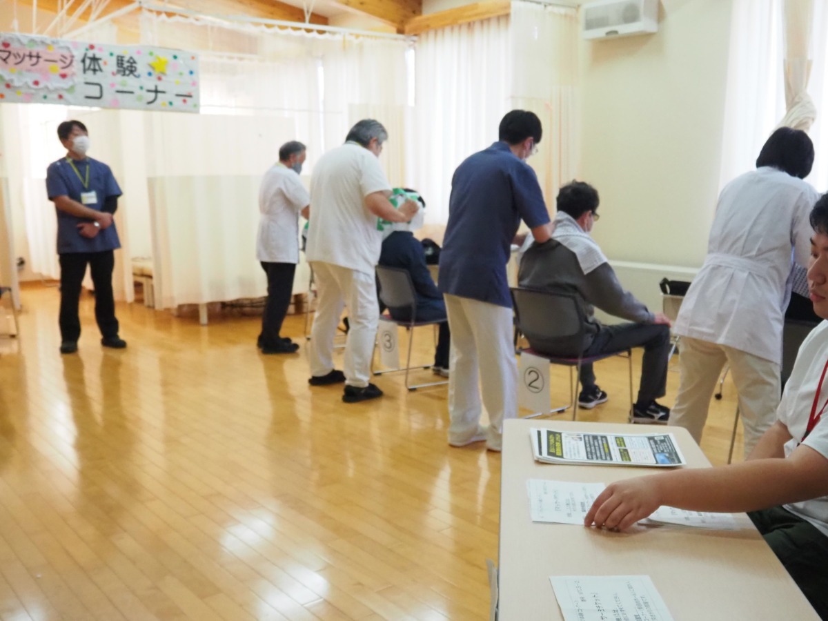 理療科生徒職員4名が、椅子に座っている体験者に施術をしている様子