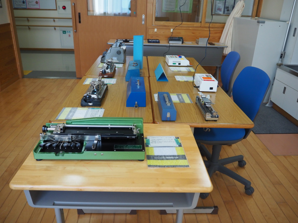 教室の中央に集められた5つの机に、各点字機器が並んでいる様子