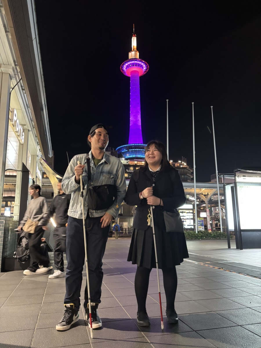 ピンク色にライトアップされたタワーを背景に生徒が並んでいる様子