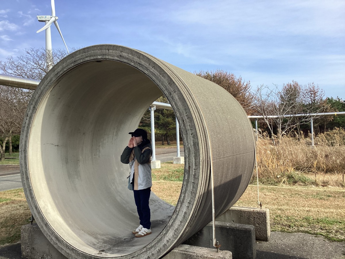 野外に置いてある実際の下水道管の模型の中で生徒が声を出すふりをしている様子
