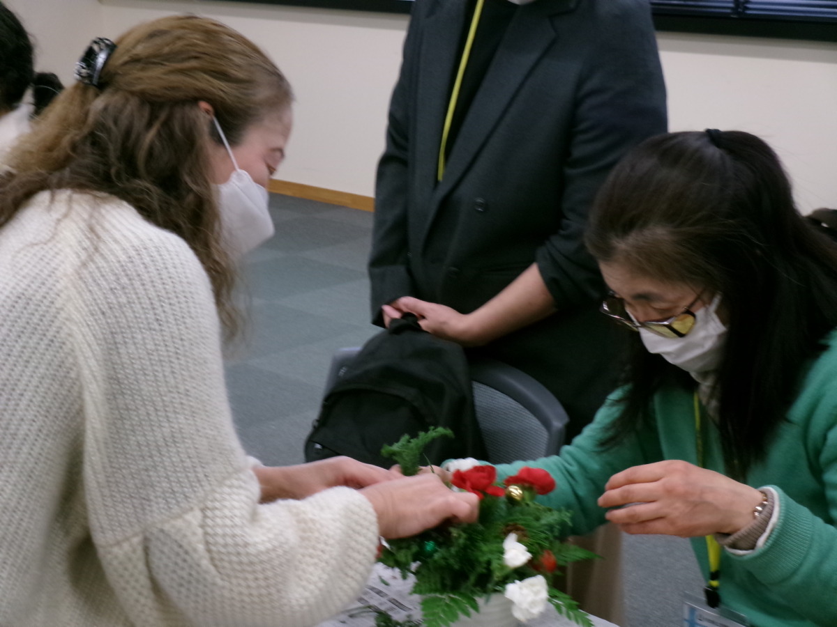 講師の先生が参加者と花を挟む形で向かい合って指導している様子