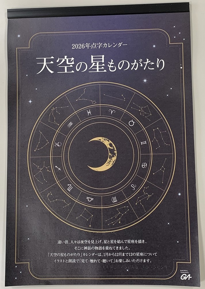 黒い星空の背景に白文字で「2026点字カレンダー　天空の星ものがたり」と書かれており、十二星座が月を中心として円状にプリントされている