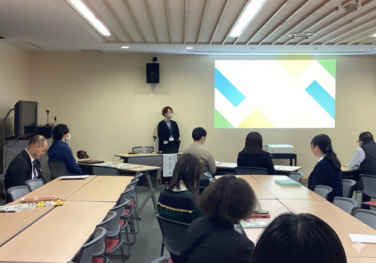 壁に映したスライドの前で話す講師と、手前に並べられた椅子に座っている生徒と職員