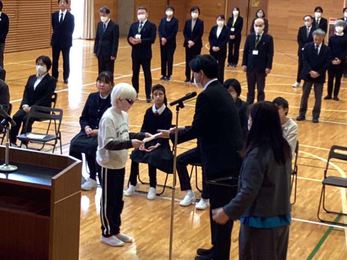 演台の手前で、図書委員長の生徒から、受賞した児童へ賞状を授与している様子