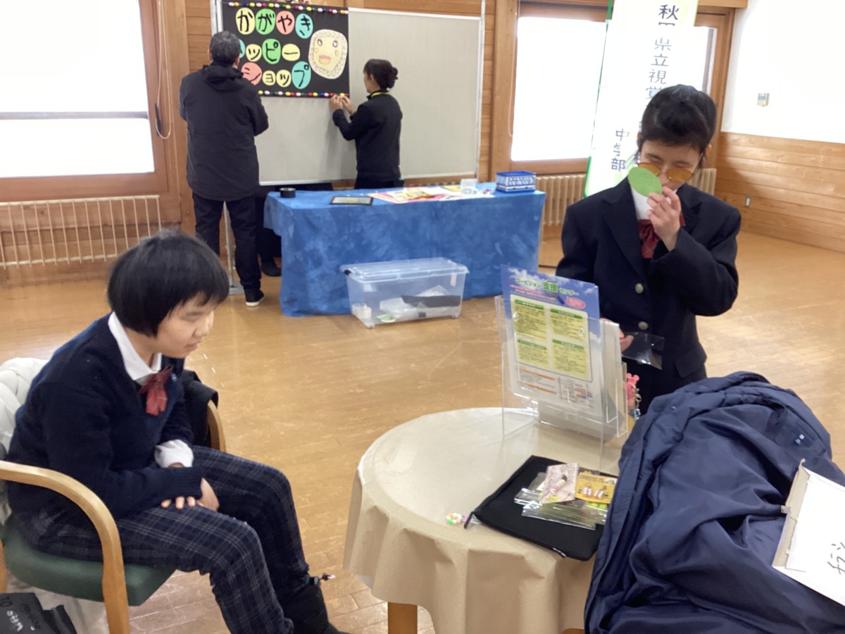 上着などの荷物を置いているテーブルの近くに、椅子に腰かけるなどして生徒が集まっている様子