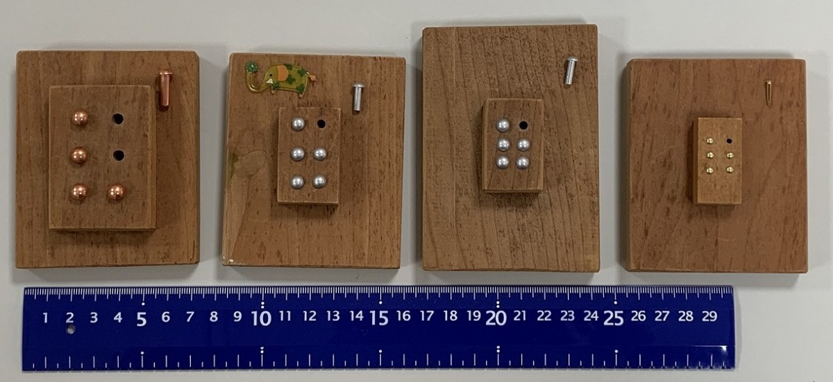 写真：リベット式の点字導入教材。左から、リベットの大きさが大、中、小となっており、中サイズのものは、リベットの間隔が広いものと狭いものの2種類ある