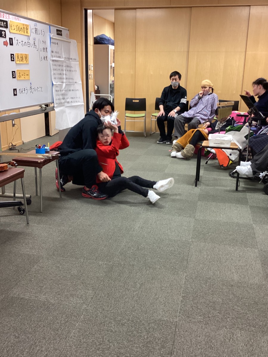 きらりの生徒が前方で、白い馬の人形を掲げて見せている様子