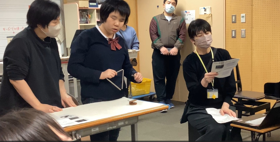 視覚の生徒が立ってトライアングルを演奏している様子