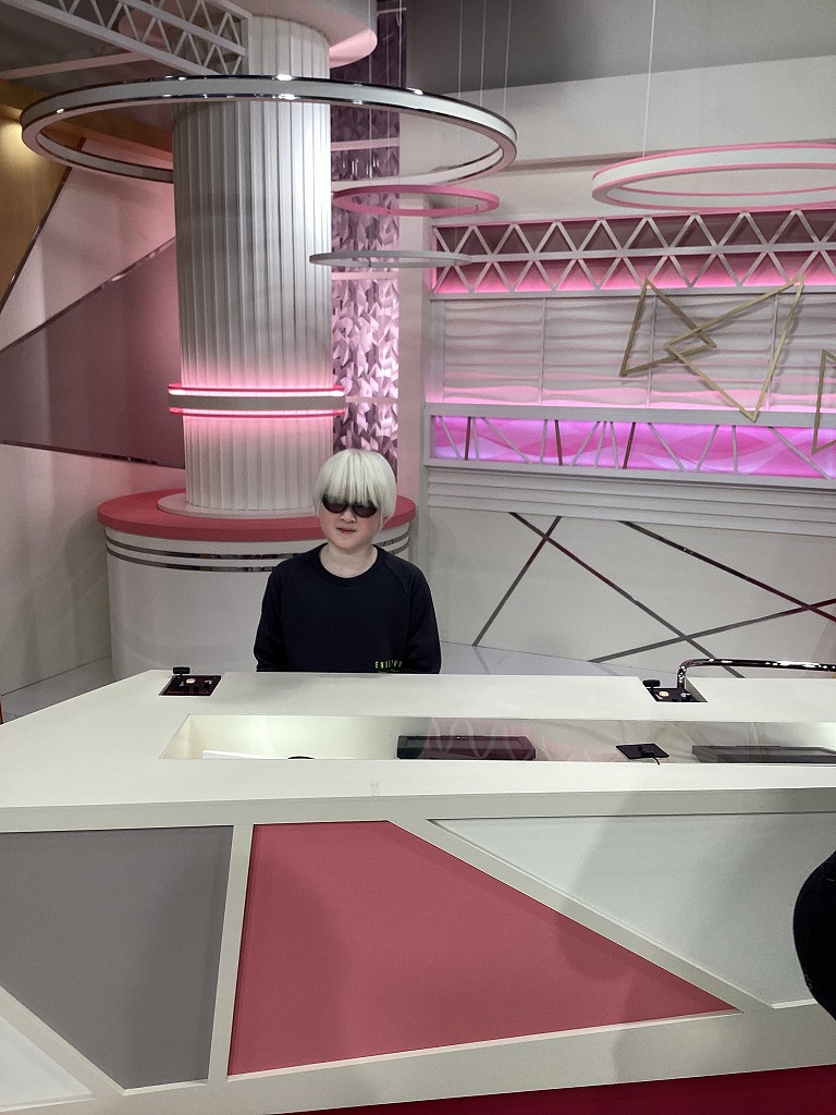 児童がニュース番組のセット内の、アナウンサー席に座っている様子