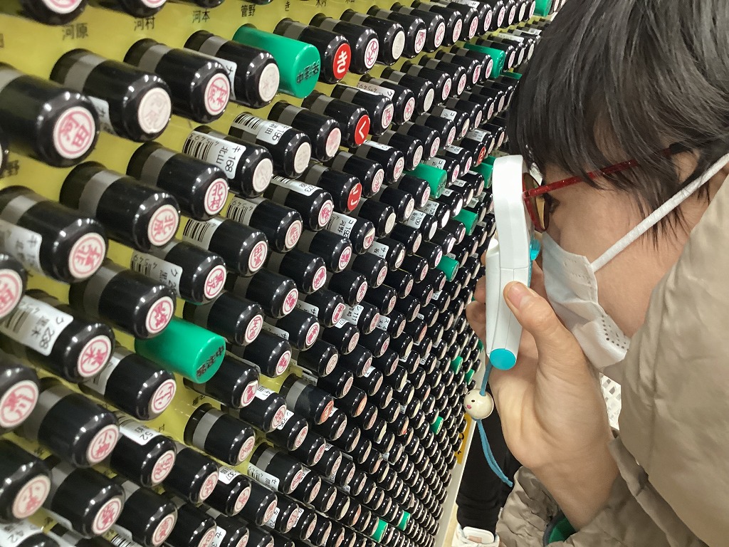 たくさんあるハンコの中から、ルーペを使って目当ての名字を探している児童の様子