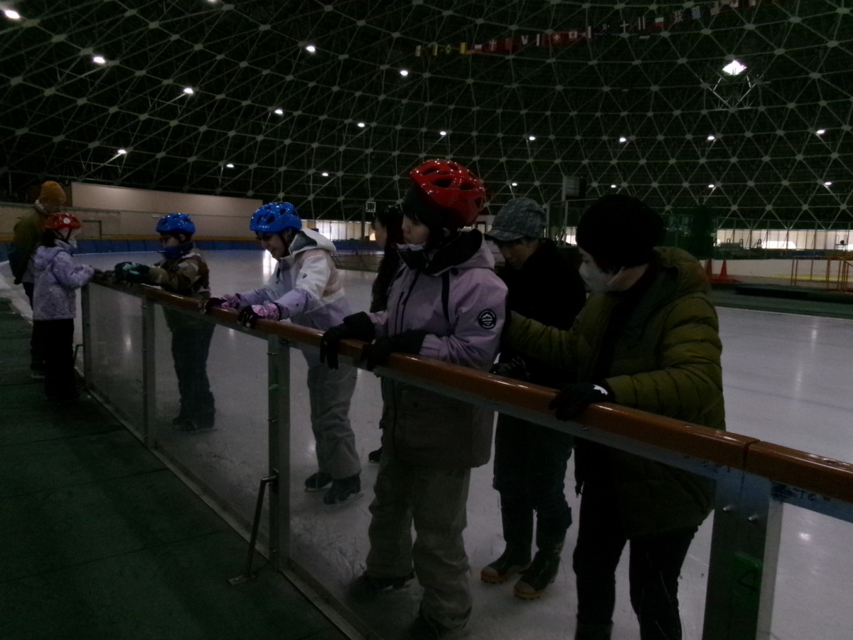 児童3名が、リンク沿いの手すりにつかまりながら並んで横歩きをしている様子