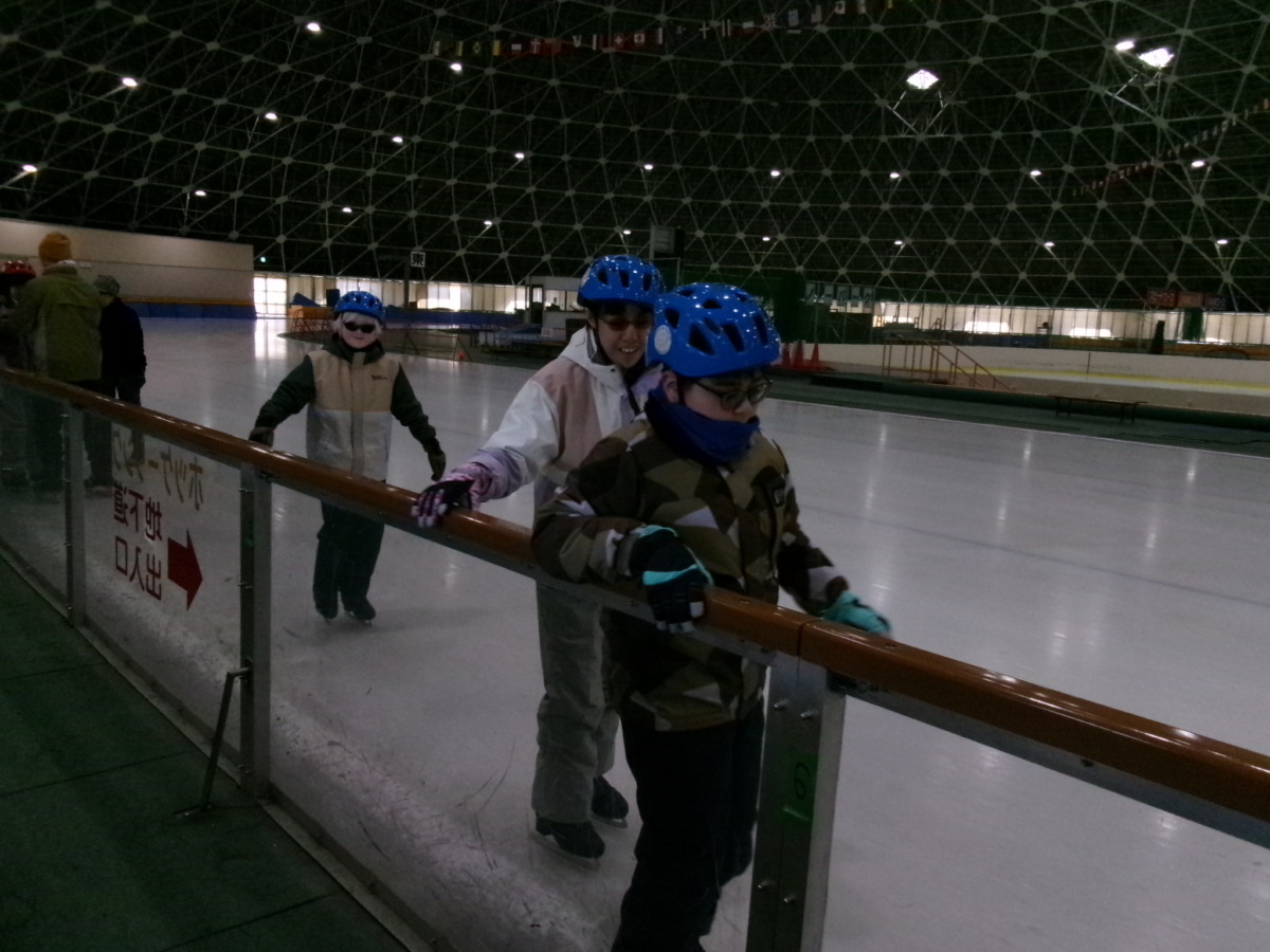 児童3名のうち、前の2名は手すりをつかみながら進行方向に向かって歩き、後ろの1名は手すりを使わずに歩いている様子