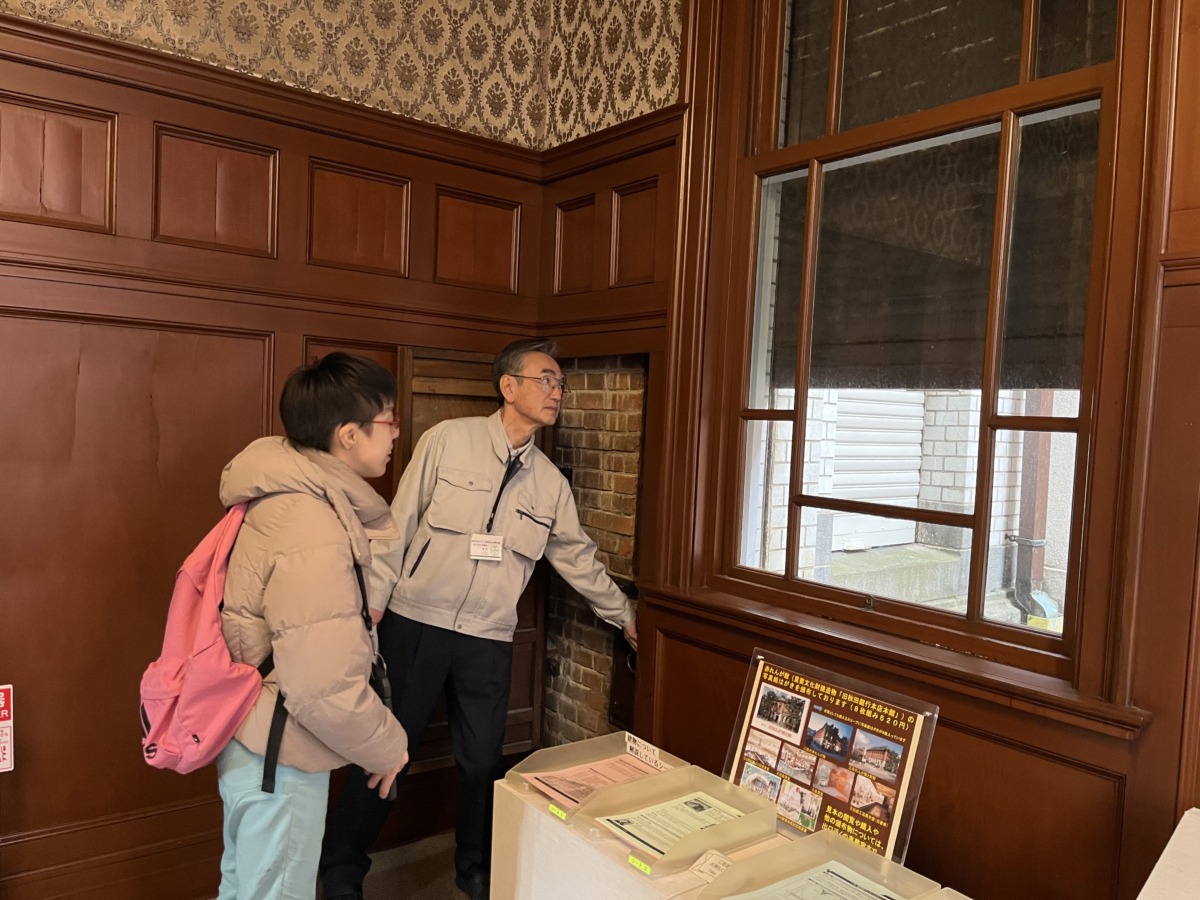 児童が建物の中から、窓の外に設置されているシャッターが下りてくるのを見ている様子。