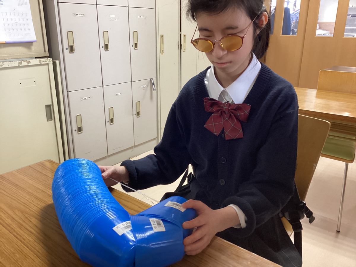 机の上に乗った、重ねられている植物用のポットのラベルを確認している様子