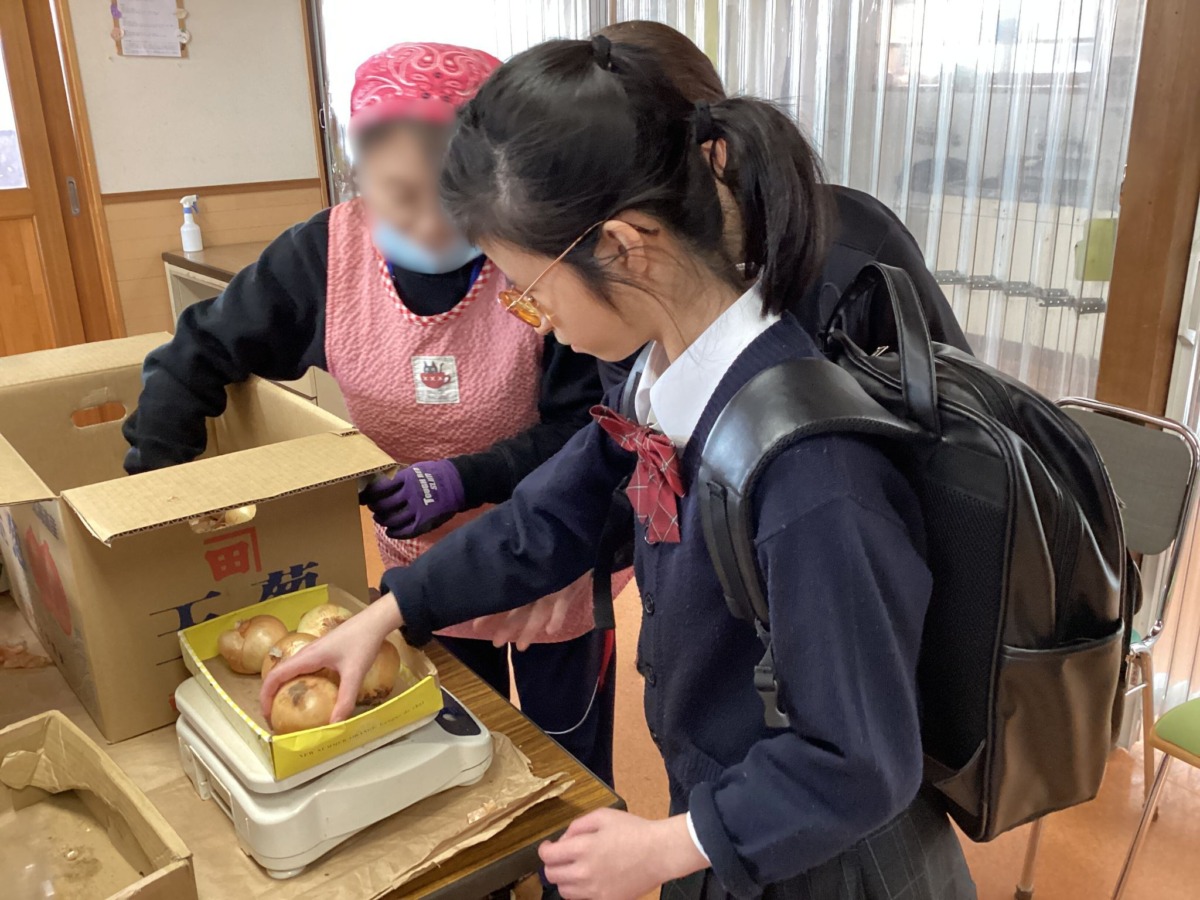 電子量りの上に玉ねぎを乗せて、重さをはかっている様子