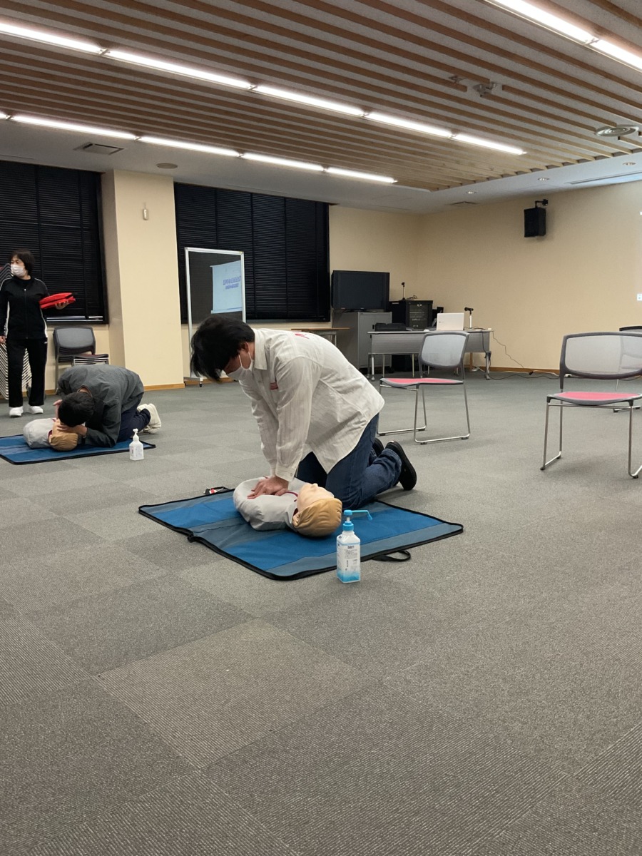 生徒が、マットに横たわっている人の半身模型に胸骨圧迫をしている様子。