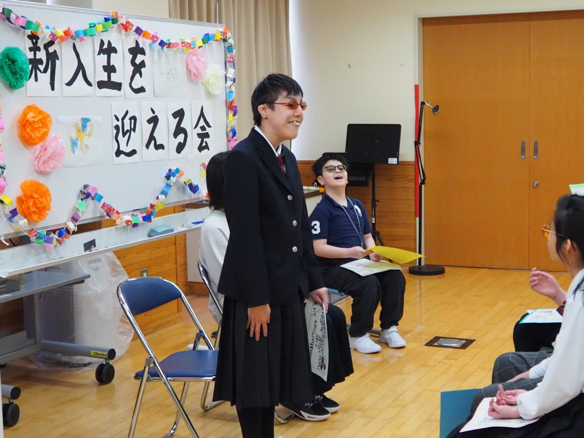 新入生が全体の前に立ち、自己紹介をしている様子