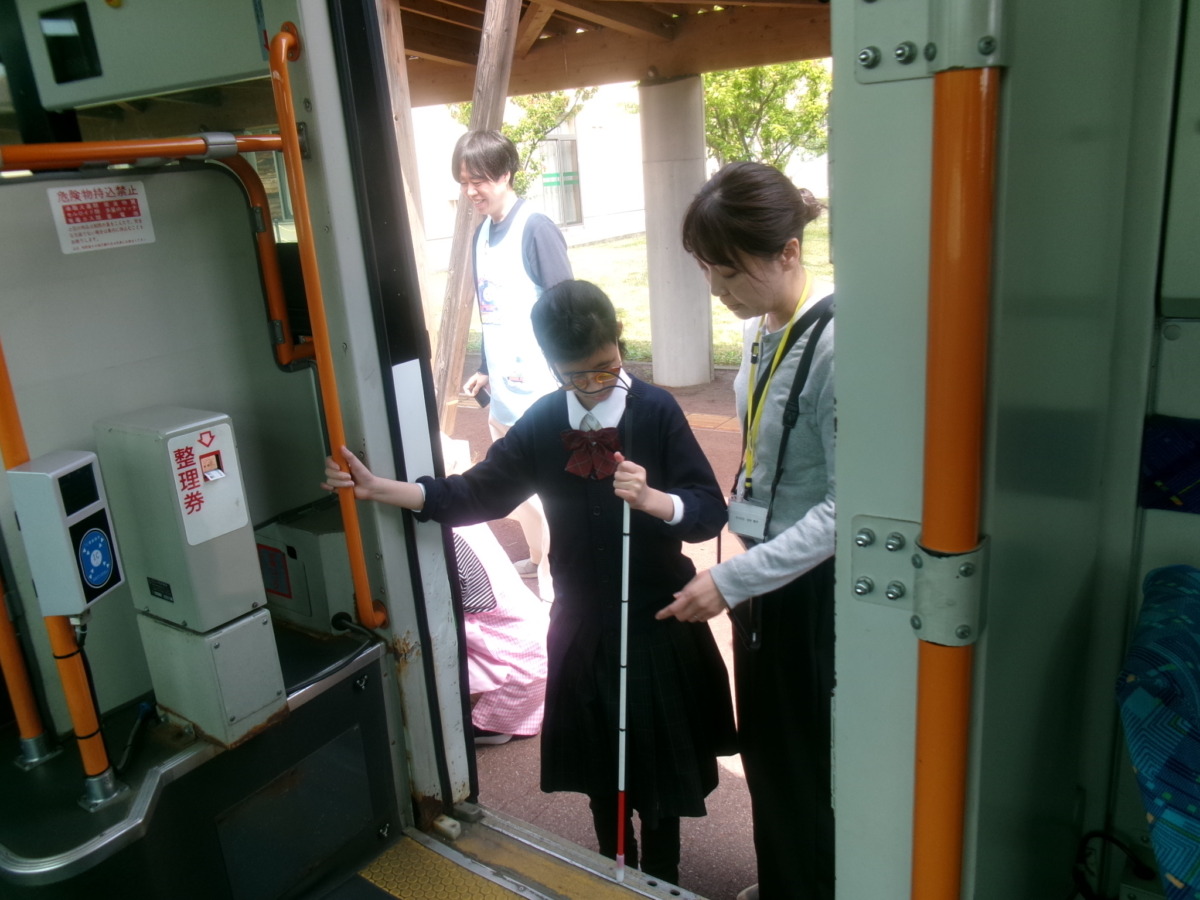 職員に付き添ってもらいながら、白杖を乗車口の段差に当てて高さを確認している生徒の様子。