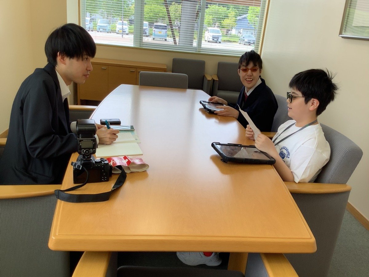 児童生徒二名が、取材にいらっしゃった秋田さきがけ新報の方とテーブルを挟んで話している様子。