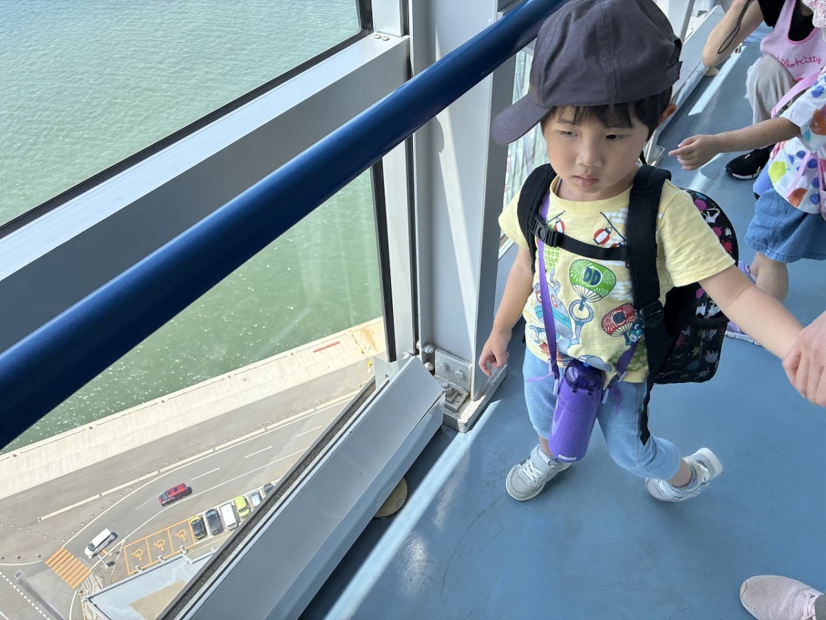 職員と手を繋ぎながら展望台のガラスの傍を歩いている児童の様子。