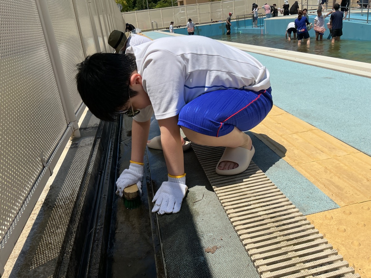 ブラシで側溝の底面をこすっている児童の様子。